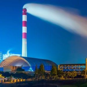 Factory With Smoke Stack Against Sky At Night.